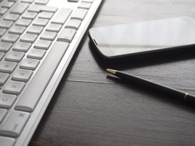 Toetsenbord, pen en telefoon op een bureau, symbool voor boekhouding en administratief werk