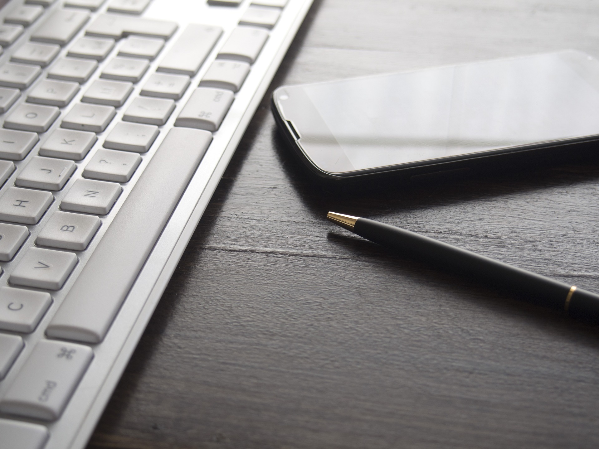 Toetsenbord, pen en telefoon op een bureau, symbool voor boekhouding en administratief werk