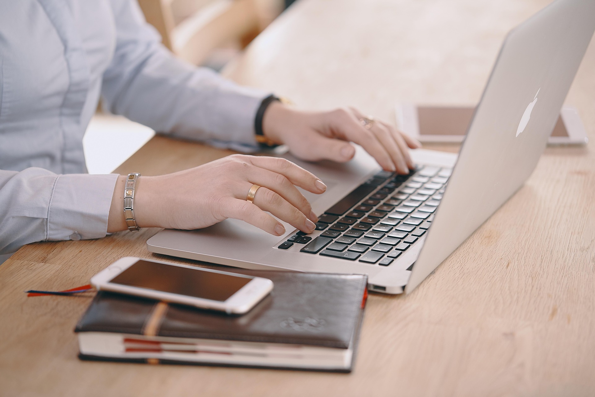 Vrouw werkt op laptop met agenda, telefoon en tablet naast zich, voor overzicht en planning