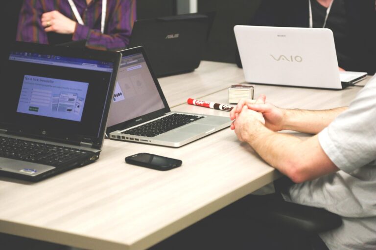 Mensen in overleg rond een tafel met laptops en notities